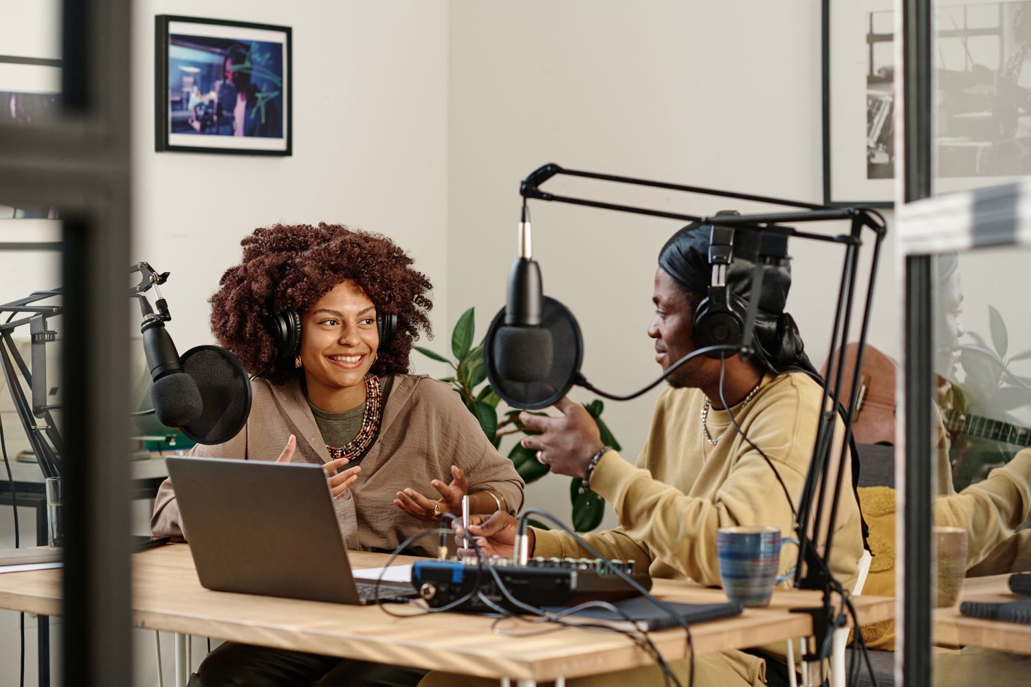 Happy young female host or radio presenter talking to invited guest sitting in front of her during discussion of main points of podcast